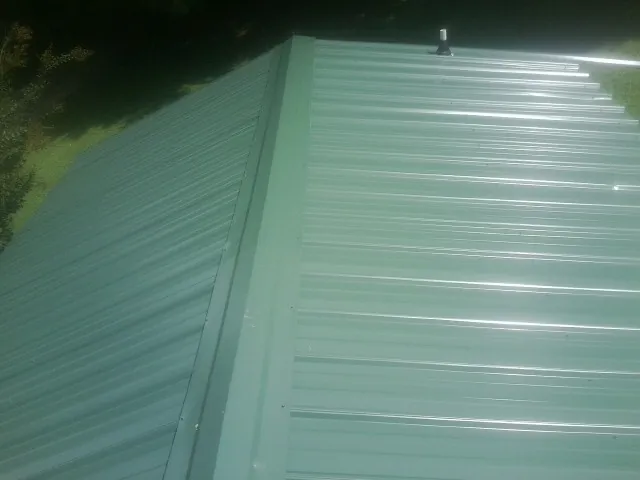 New green metal panels meeting at the ridge of a roof — Flat Roof Repair work by our crew in Tillamook