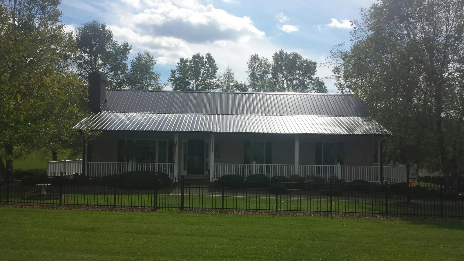 Gray metal roof on a brick ranch with a full width front porch — Gutter Guard Installation work by our crew in Tillamook