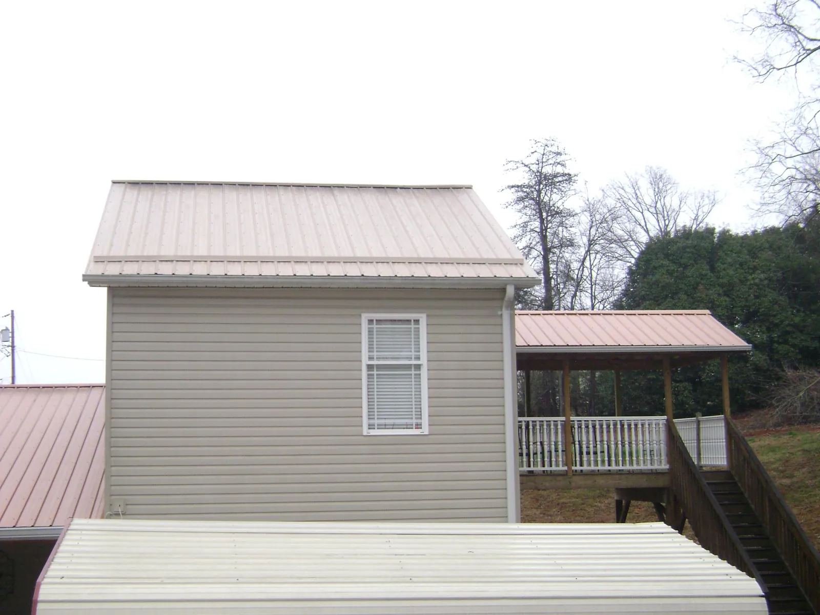 Tan metal roofs on a two story addition and attached porch, from a Roof Replacement job in Tillamook